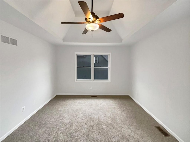 unfurnished room with a raised ceiling, baseboards, visible vents, and carpet floors