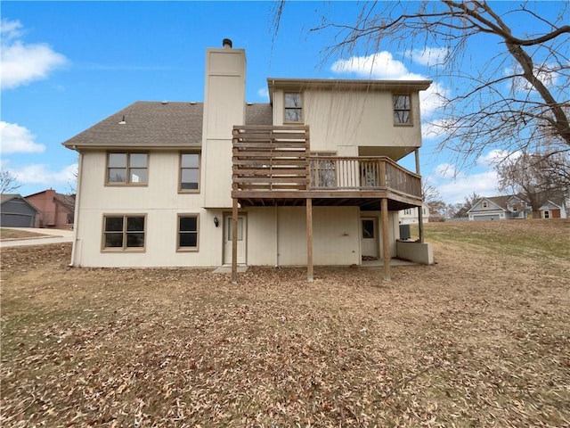 rear view of property featuring a wooden deck, roof with shingles, and a chimney