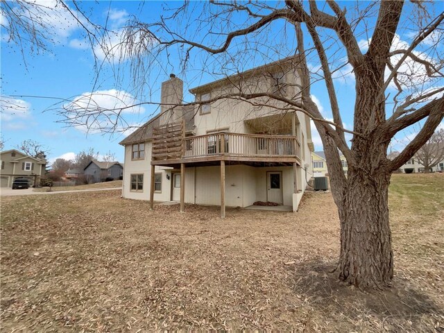 back of property with a wooden deck, central AC unit, and a chimney