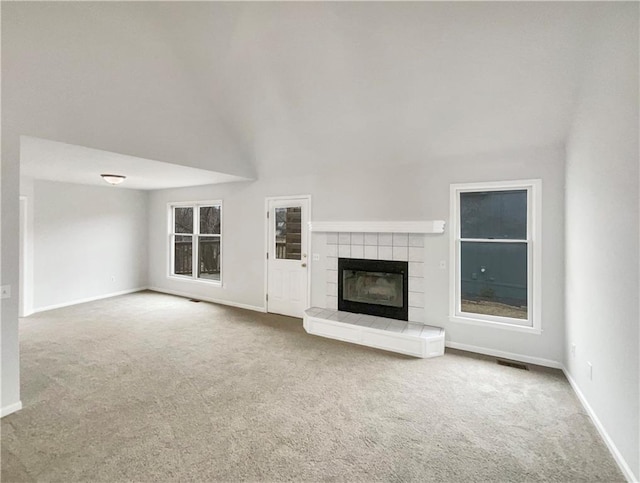 unfurnished living room with visible vents, a tile fireplace, baseboards, and carpet floors