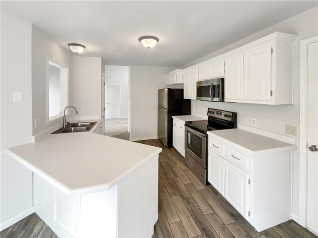 kitchen featuring dark wood finished floors, a sink, light countertops, white cabinets, and appliances with stainless steel finishes