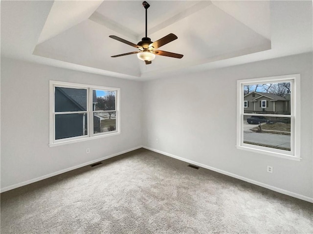 unfurnished room with visible vents, carpet flooring, a raised ceiling, and baseboards