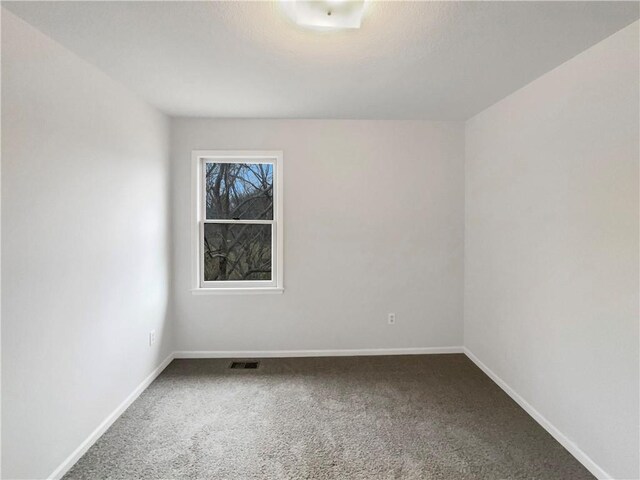 carpeted empty room with visible vents and baseboards