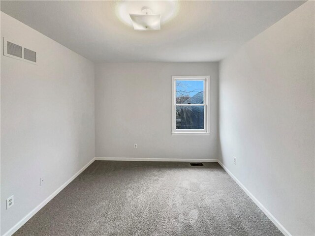 carpeted empty room featuring baseboards and visible vents