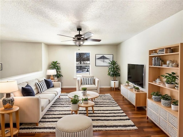 living room with baseboards, a ceiling fan, dark wood-style flooring, and a textured ceiling