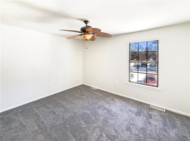 empty room with dark colored carpet, visible vents, baseboards, and a textured ceiling