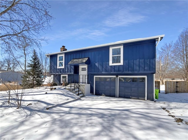 raised ranch featuring a garage, fence, board and batten siding, and a chimney