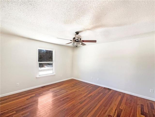 spare room with visible vents, a ceiling fan, a textured ceiling, hardwood / wood-style floors, and baseboards