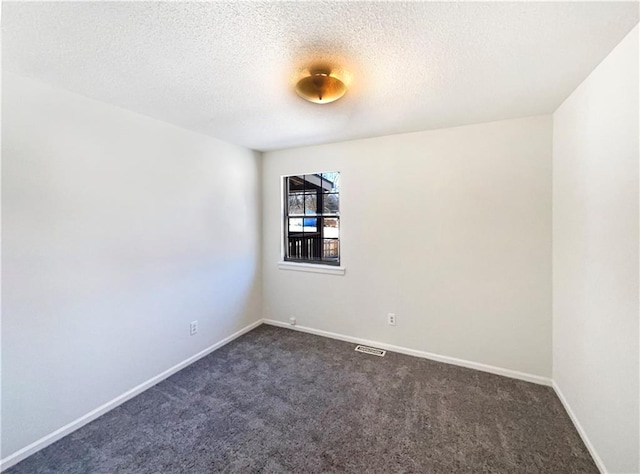 empty room featuring dark colored carpet, baseboards, and a textured ceiling