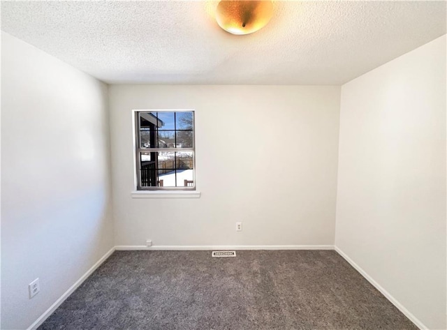 spare room with a textured ceiling, baseboards, and carpet