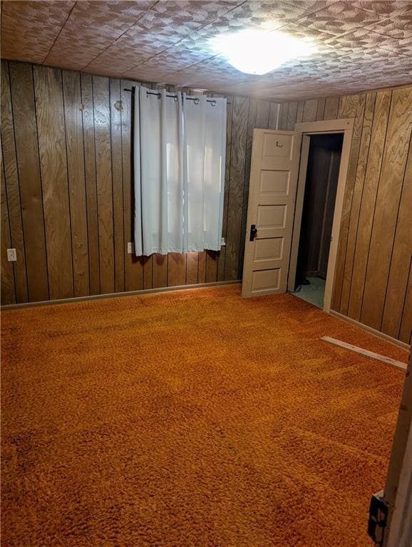 spare room featuring carpet floors and wooden walls