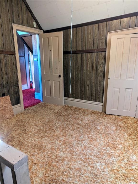 empty room with carpet flooring, wood walls, and vaulted ceiling