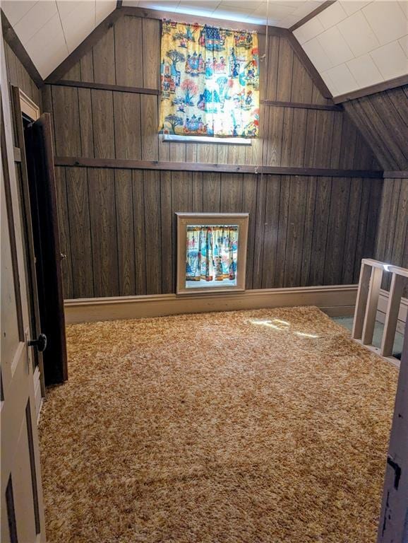 bonus room featuring lofted ceiling, wooden walls, and carpet