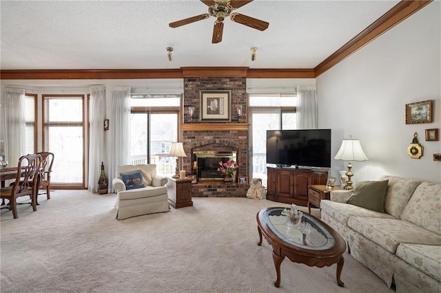 living room with ceiling fan, ornamental molding, a textured ceiling, a brick fireplace, and carpet flooring