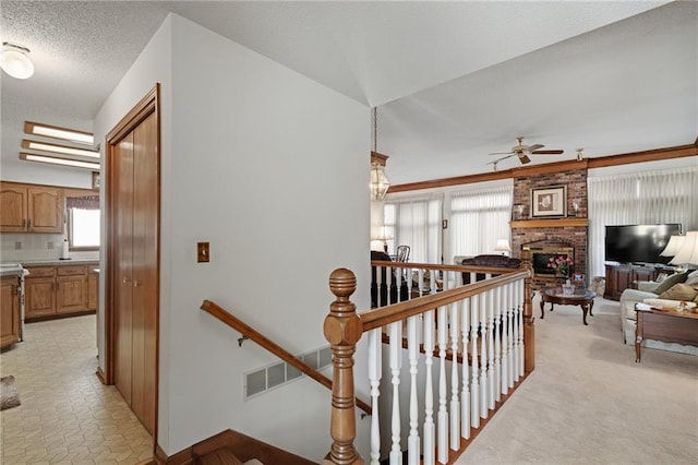 corridor with visible vents, an upstairs landing, and a textured ceiling