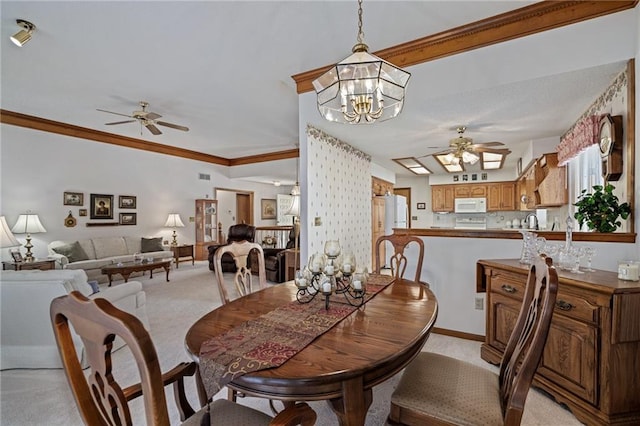 dining room with light colored carpet, ceiling fan with notable chandelier, crown molding, and baseboards