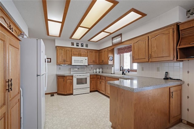 kitchen featuring brown cabinets, a sink, backsplash, white appliances, and a peninsula