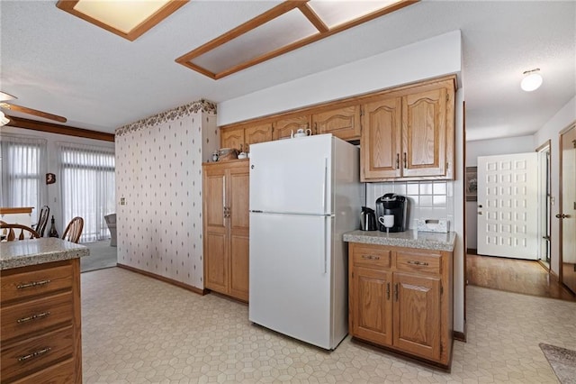 kitchen featuring light floors, brown cabinets, and freestanding refrigerator