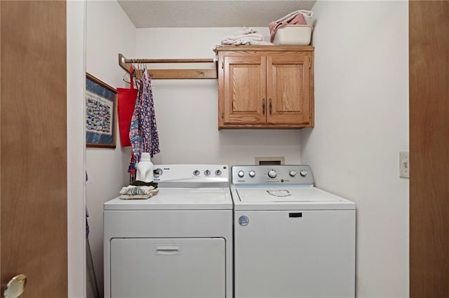 laundry area with cabinet space, a textured ceiling, and washer and clothes dryer