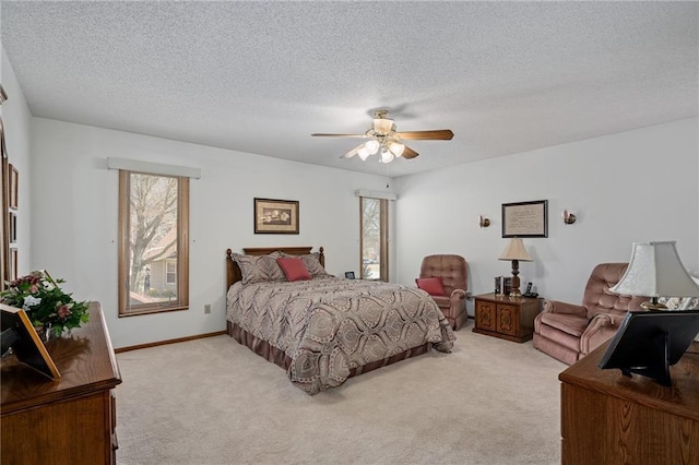 bedroom featuring baseboards, light colored carpet, a ceiling fan, and a textured ceiling