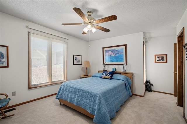 bedroom featuring light carpet, ceiling fan, a textured ceiling, and baseboards