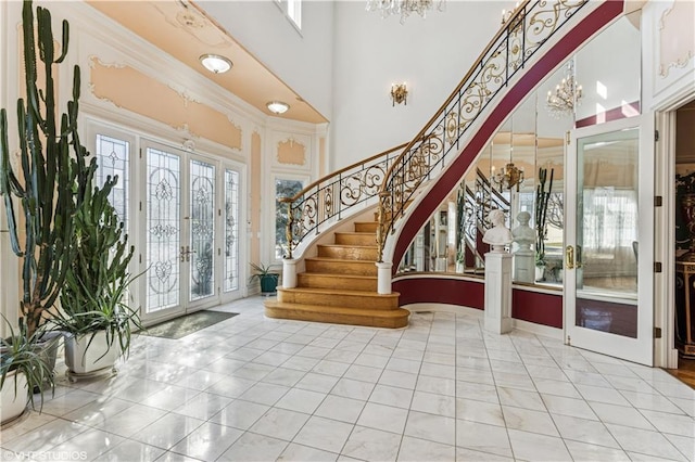 tiled entryway with arched walkways, stairs, french doors, a towering ceiling, and a chandelier