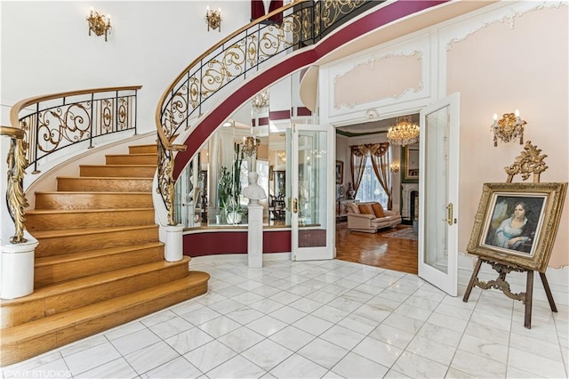 entrance foyer with french doors, arched walkways, a high ceiling, and stairway