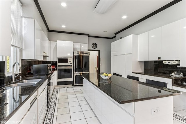 kitchen with refrigerator, built in microwave, ornamental molding, a sink, and stainless steel oven