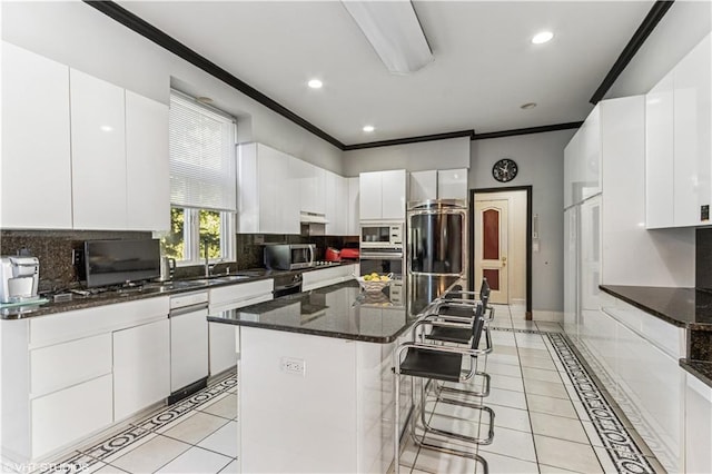 kitchen with a breakfast bar area, light tile patterned flooring, ornamental molding, white cabinets, and appliances with stainless steel finishes