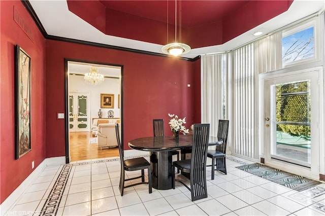 dining space with a raised ceiling, ornamental molding, tile patterned flooring, baseboards, and a chandelier