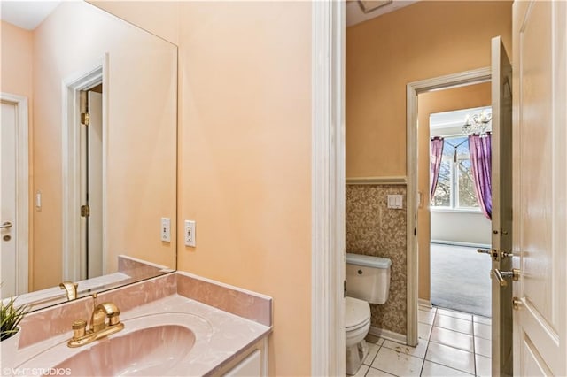 half bathroom with tile patterned floors, baseboards, toilet, and vanity