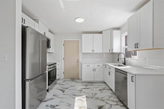 kitchen featuring tasteful backsplash, marble finish floor, appliances with stainless steel finishes, and a sink