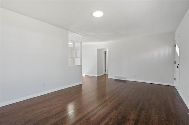 unfurnished room featuring visible vents, baseboards, and dark wood-style flooring