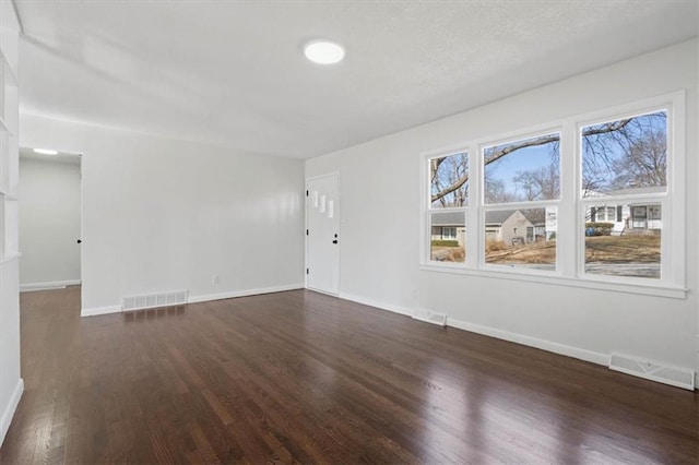 unfurnished room with visible vents, baseboards, and dark wood-style flooring