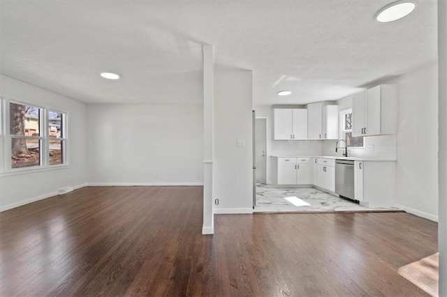 unfurnished living room featuring a textured ceiling, baseboards, and wood finished floors