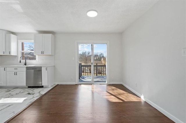 interior space featuring light wood finished floors, a textured ceiling, baseboards, and a sink