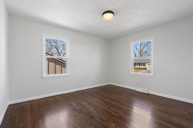 empty room with visible vents, dark wood-style floors, baseboards, and a textured ceiling