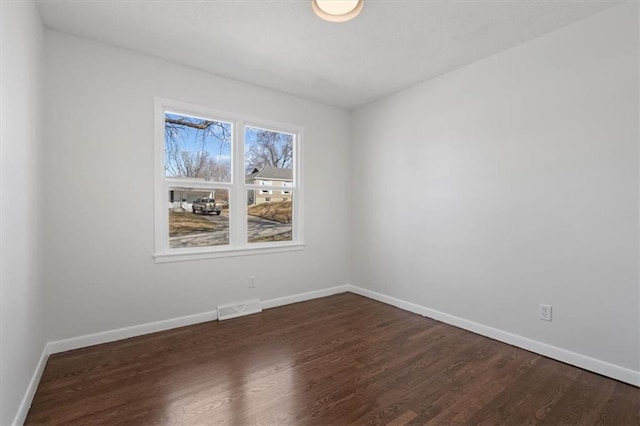 empty room featuring visible vents, baseboards, and dark wood-type flooring