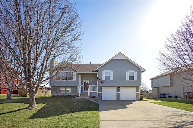 bi-level home featuring stone siding, concrete driveway, a front yard, a garage, and a chimney