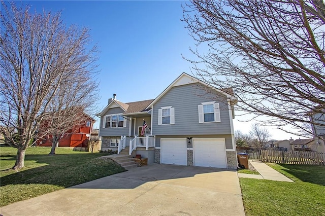 split foyer home featuring fence, concrete driveway, a front yard, a garage, and stone siding