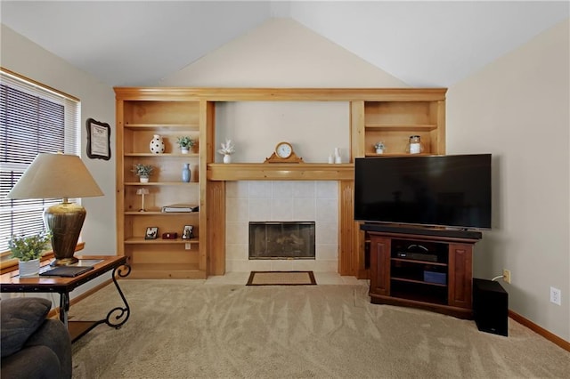 living area with a tiled fireplace, lofted ceiling, plenty of natural light, and carpet floors