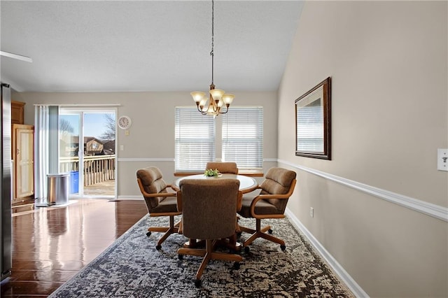 dining area with baseboards, a notable chandelier, wood finished floors, and vaulted ceiling