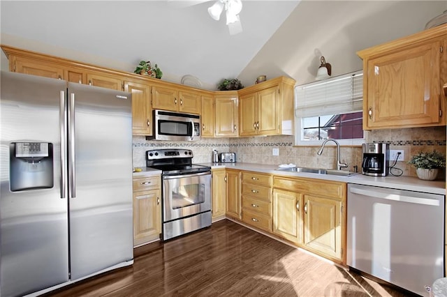 kitchen with vaulted ceiling, appliances with stainless steel finishes, light countertops, and a sink