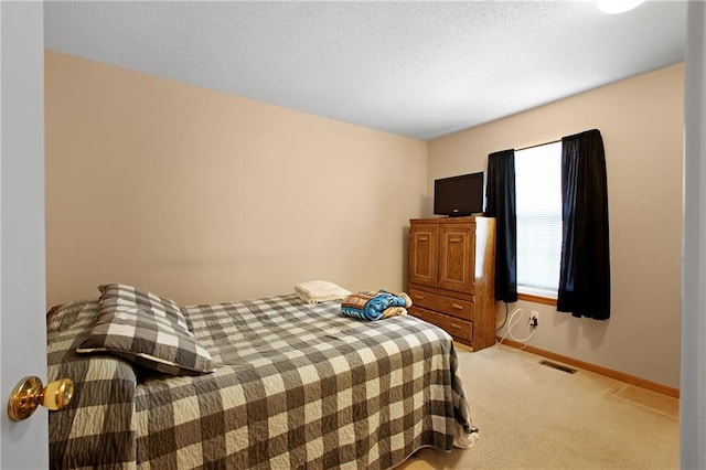 bedroom featuring visible vents, light colored carpet, baseboards, and a textured ceiling