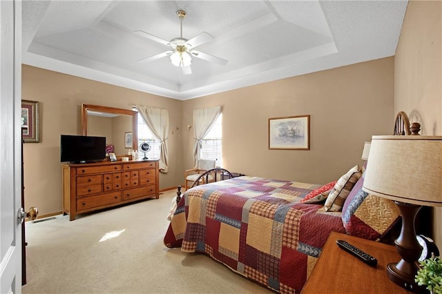 bedroom featuring a tray ceiling, baseboards, ceiling fan, and carpet flooring