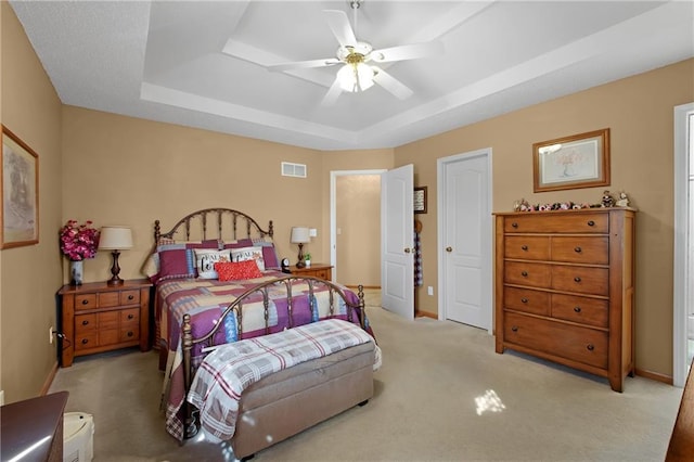 bedroom with visible vents, a tray ceiling, carpet floors, baseboards, and ceiling fan