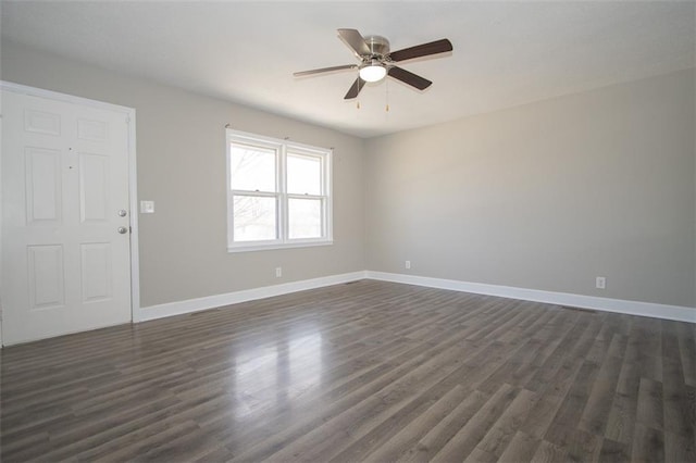 spare room with baseboards, ceiling fan, and dark wood-style flooring