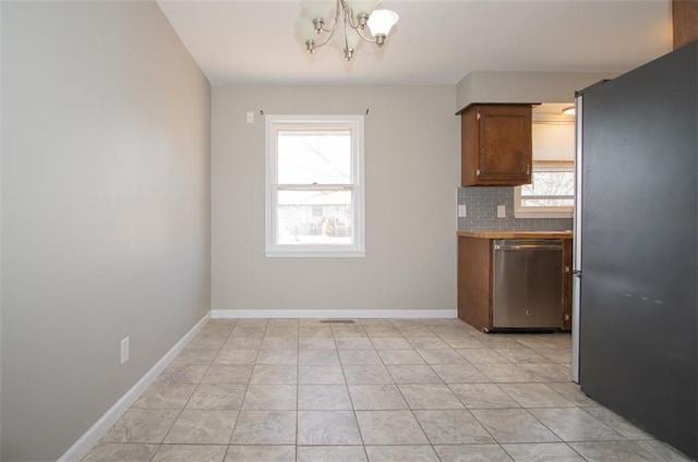 kitchen featuring baseboards, tasteful backsplash, appliances with stainless steel finishes, and a chandelier