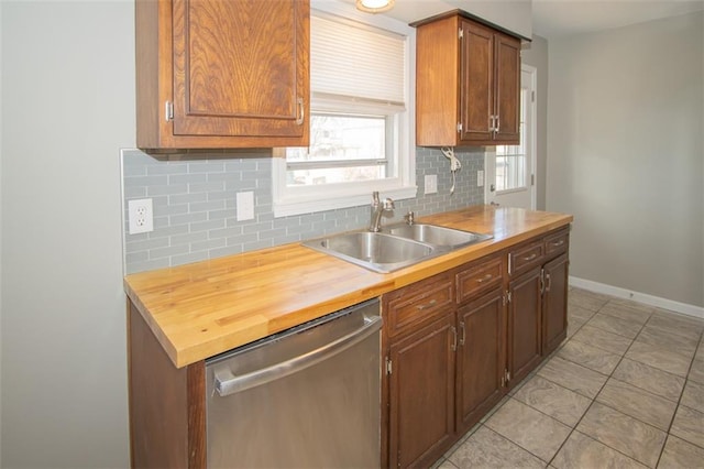 kitchen with a sink, backsplash, butcher block counters, baseboards, and dishwasher