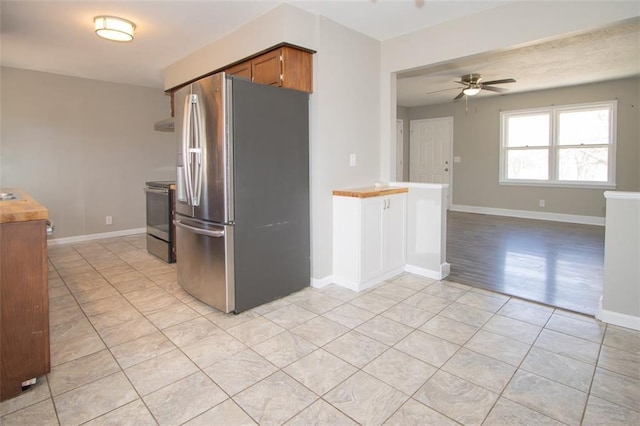 kitchen with baseboards, ceiling fan, light tile patterned floors, brown cabinets, and stainless steel appliances